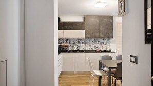 A modern kitchen with white cabinets, a wooden countertop, and a dining area with a table and chairs. - Apartment 'Giorgia - Caspoggio' with Mountain View, Shared Garden and Balcony (Caspoggio)