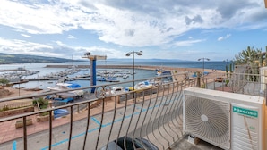 Un puerto deportivo con barcos, una playa y vista al mar.