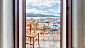 Un balcón con vistas a un puerto deportivo, una silla y piso de baldosas.