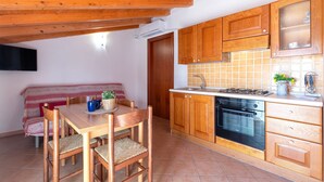 Una cocina con armarios de madera, una estufa y un comedor con mesa y sillas.