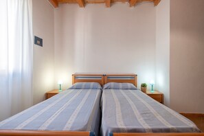 A double bed with a wooden headboard, two bedside tables with lamps, and a power outlet on the wall.
