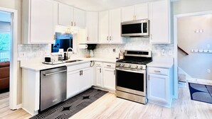 A modern kitchen with white cabinets, stainless steel appliances, and a black and white patterned rug.
