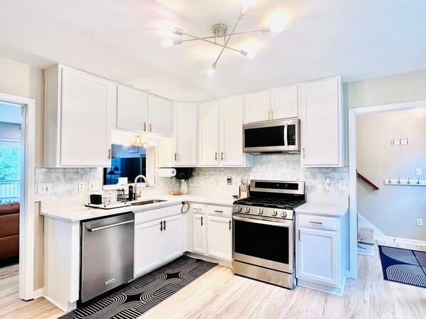 A modern kitchen with white cabinets, stainless steel appliances, and a black and white patterned rug.