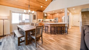 A spacious kitchen with wooden cabinets, a large island, and a dining area with a wooden table and chairs.