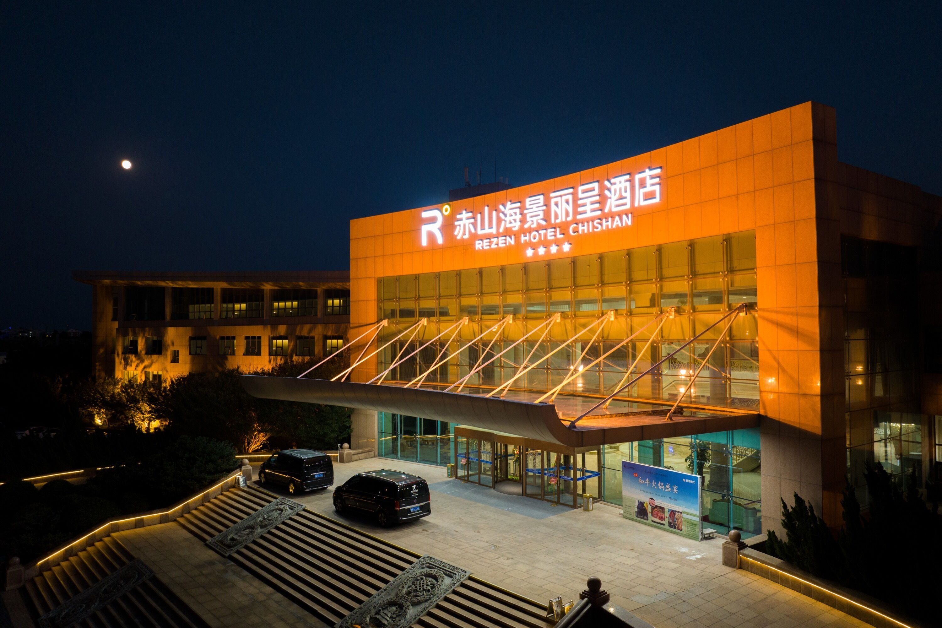 A hotel with a modern design, featuring a prominent entrance and a sign in a foreign language.
