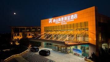 A hotel with a modern design, featuring a prominent entrance and a sign in a foreign language.