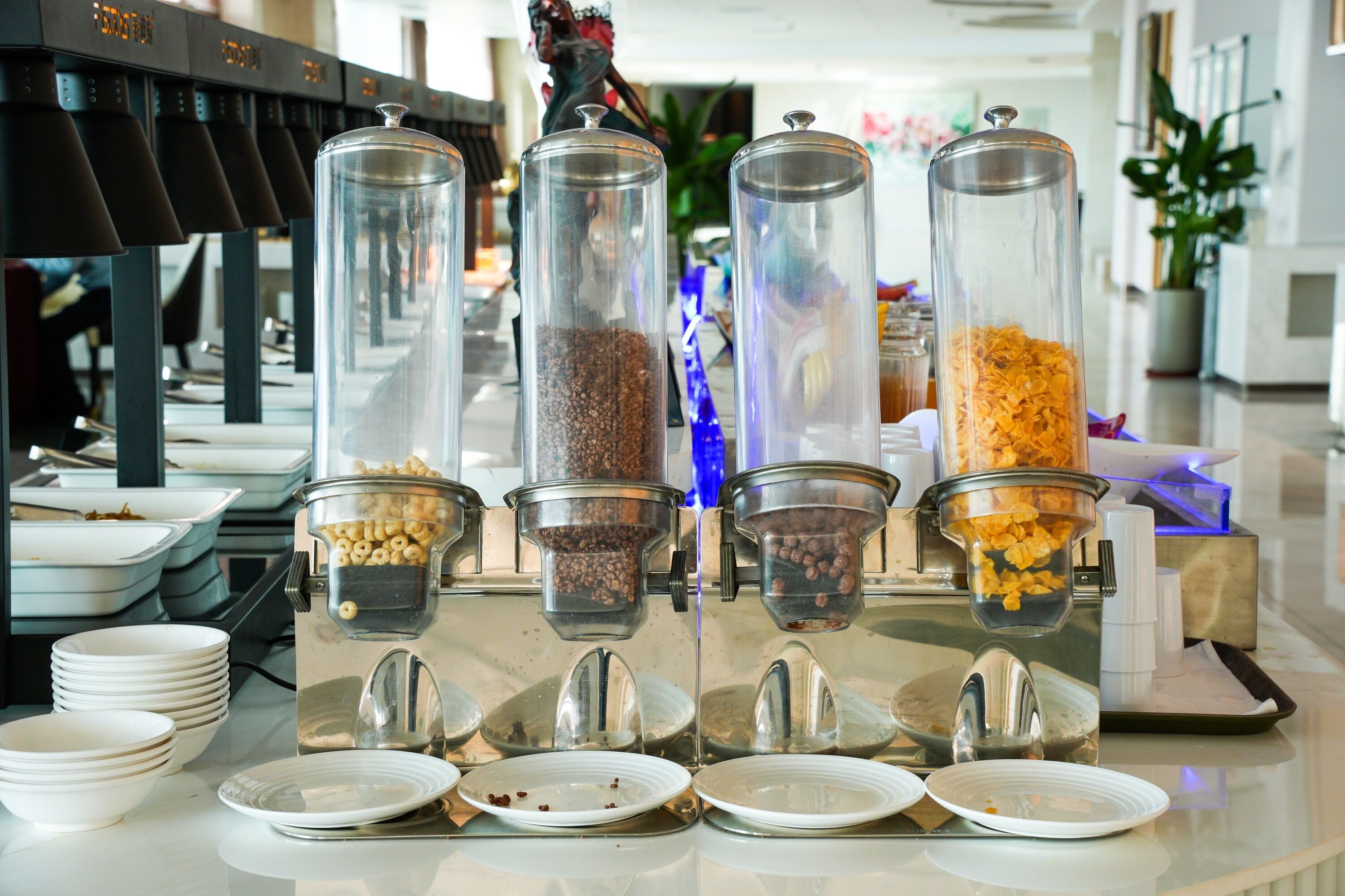 A buffet setup with multiple coffee dispensers and a variety of food containers.