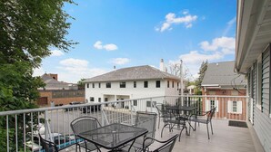 A balcony with outdoor furniture, a view of a white building, and a clear sky. - Neighboring suites in central heart of town! Perfect for couples! Walk to Town, Balcony, & Parking (Lake Geneva)