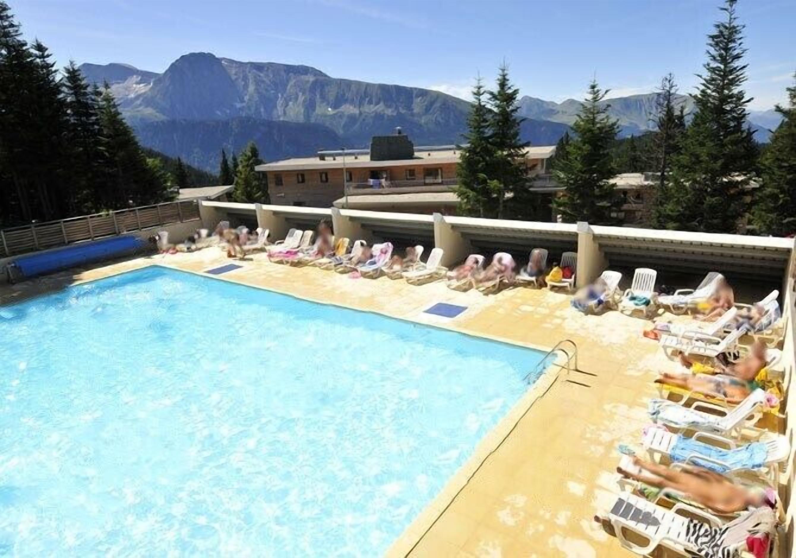 Poolbereich mit Liegestühlen und Bergblick.