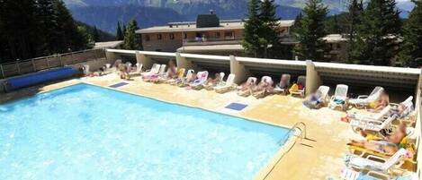 Poolbereich mit Liegestühlen und Bergblick.