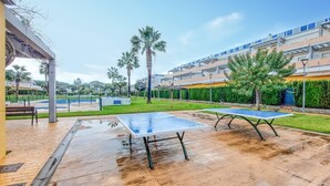 An outdoor area with a ping pong table, a basketball court, and a swimming pool.