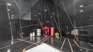 Une cuisine moderne avec des plans de travail en marbre noir, une machine à café rouge et un moulin à café.