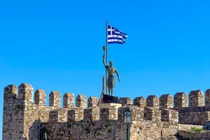 A statue of a figure holding a flag on a stone wall with crenellations.
