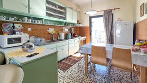 A kitchen with a dining table, chairs, a refrigerator, and various kitchen appliances.