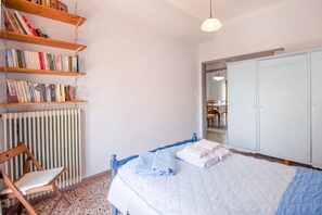 Un dormitorio con cama, una silla, un radiador, un armario y una estantería.