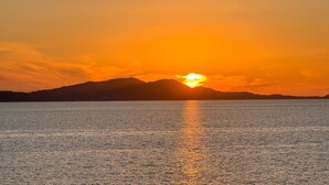 A sunset over a calm body of water with a distant mountain range.