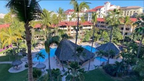 Ein Resort mit Poolbereich, Palmen und Hütten mit Reetdach.
