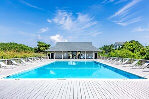 A swimming pool with lounge chairs and a covered area with a roof.