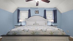 A bedroom with a bed, two bedside tables, a ceiling fan, and a window with curtains. - Spacious 4BD Waterfront Home for Fishing, Boating, & Kayaking (Gulf Shores)