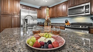 A kitchen with granite countertops, wooden cabinets, stainless steel appliances, and a charcuterie board with fruits and cheese. - Spacious 4BD Waterfront Home for Fishing, Boating, & Kayaking (Gulf Shores)