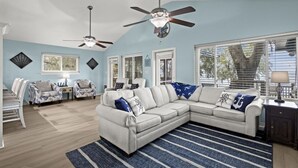 A living room with a sectional sofa, two armchairs, a dining table with chairs, and a ceiling fan. - Spacious 4BD Waterfront Home for Fishing, Boating, & Kayaking (Gulf Shores)