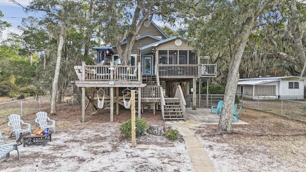 A wooden house with a deck, surrounded by trees and a fenced yard. - Spacious 4BD Waterfront Home for Fishing, Boating, & Kayaking (Gulf Shores)