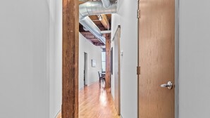A hallway with wooden flooring, a wooden door, and exposed ductwork on the ceiling. - Stylish Industrial Loft in Downtown St. Louis (St. Louis)
