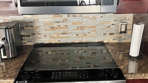 A kitchen with a stainless steel microwave, a gas stove, and a built-in oven. - Charming 3-bedroom house with Pool, Washer and Dryer and Garage in Boca Raton (Boca Raton)