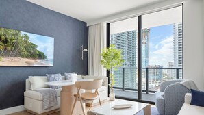 Una sala de estar moderna con un gran ventanal, un sofá, una mesa de comedor y una planta.
