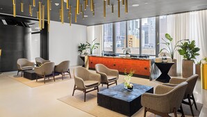 Un moderno vestíbulo de hotel con zona de estar, bar y amplios ventanales con vistas a la ciudad.