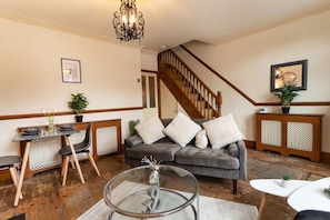A living room with a grey sofa, a wooden staircase, a dining table with chairs, and a chandelier. - Contractors*Long Stays Discounts*Parking (Eastville)