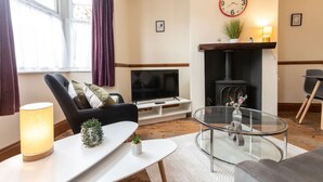 A living room with a sofa, a glass coffee table, a TV, a fireplace, and a clock on the wall.