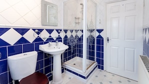 A bathroom with a white sink, a toilet, and a shower enclosure.