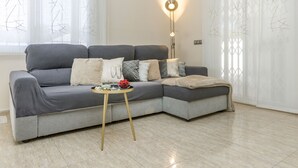Ein modernes Wohnzimmer mit einem grauen Ecksofa, einem kleinen runden Couchtisch und einer Stehlampe.