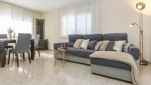 Ein modernes Wohnzimmer mit grauem Sofa, Couchtisch und Stehlampe.
