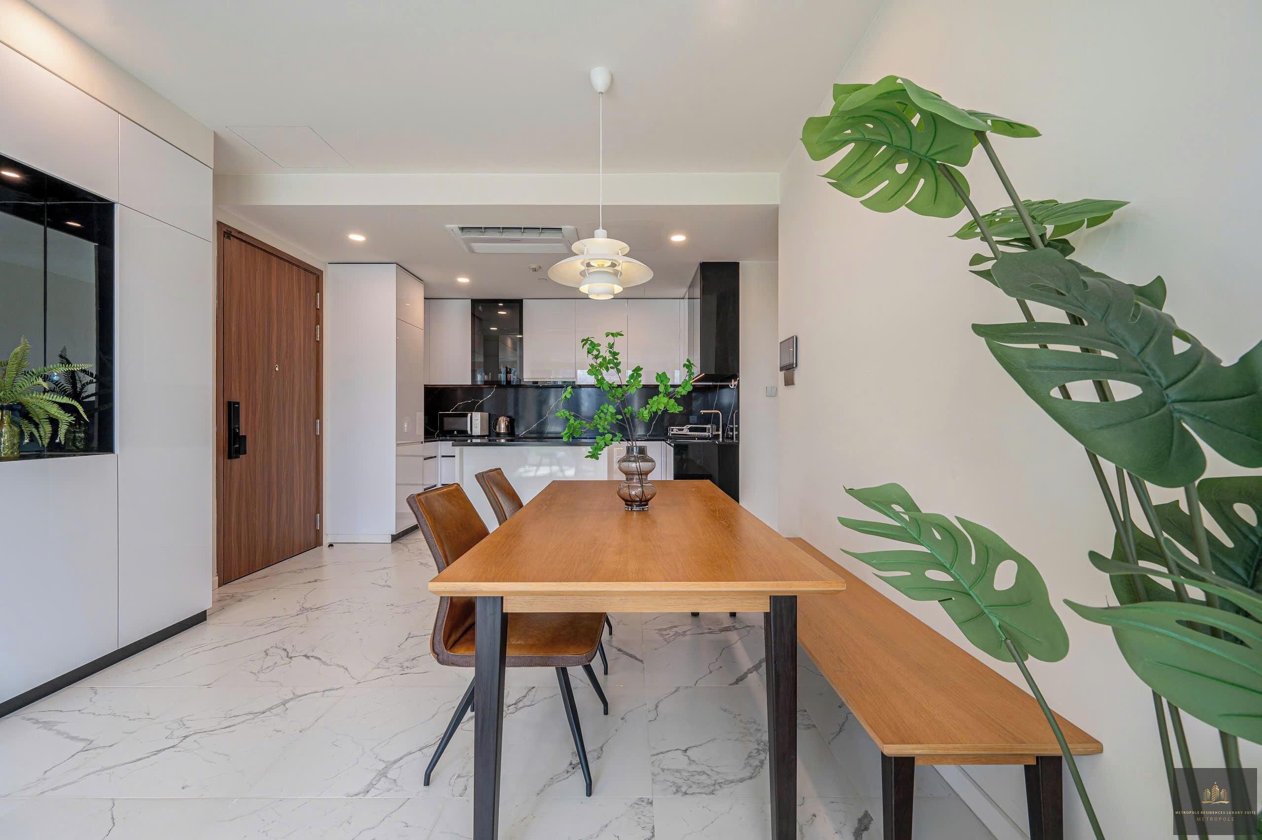 A modern dining area with a wooden table, chairs, and a hanging light fixture.