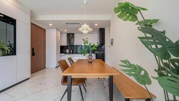 A modern dining area with a wooden table, chairs, and a hanging light fixture.