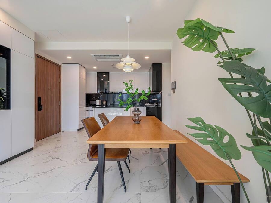 A modern dining area with a wooden table, chairs, and a hanging light fixture.