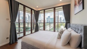 A modern bedroom with a large bed, city view, and a painting on the wall. - Metropole Residences Luxury Suite (Ho Chi Minh City)
