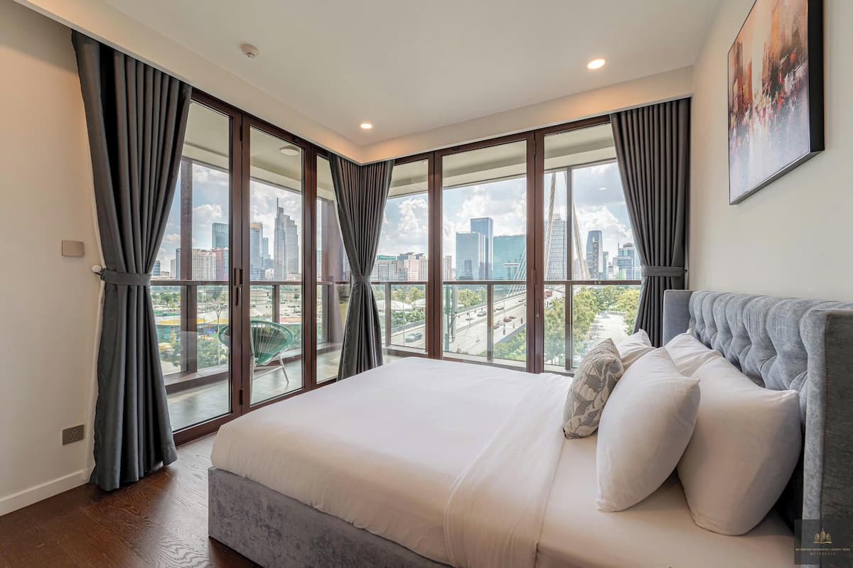 Ein modernes Schlafzimmer mit großem Bett, Blick auf die Stadt und einem Bild an der Wand.