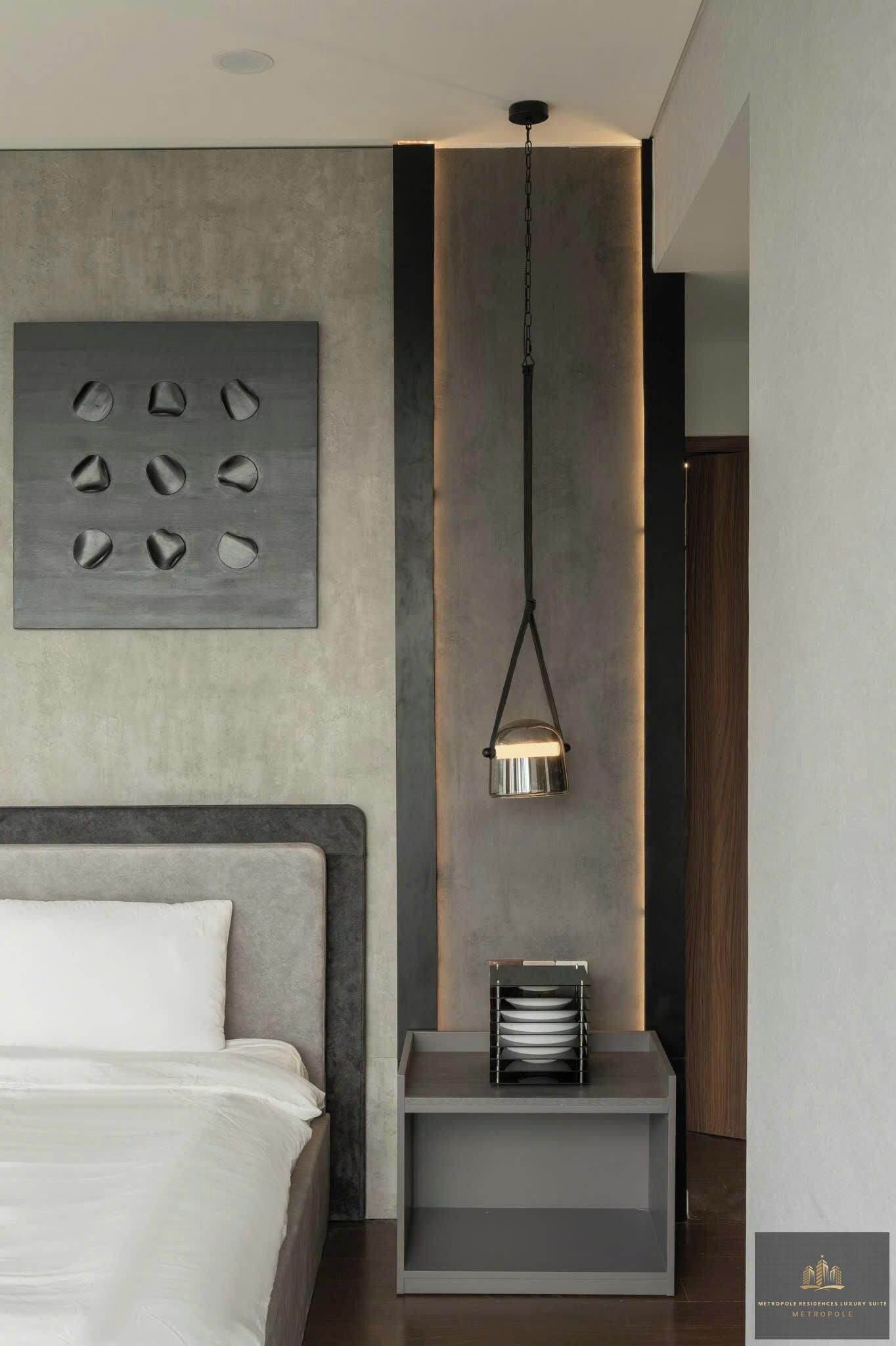 Un dormitorio moderno con cama, lámpara de pared y una mesita de noche con bandeja.