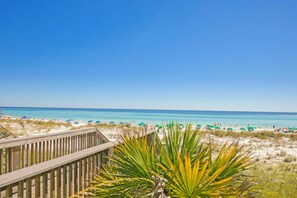 A beach with a wooden boardwalk and beach umbrellas.