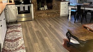 Una cocina moderna con armarios blancos, una chimenea de ladrillo, un televisor de pantalla plana y un comedor con mesa y sillas.