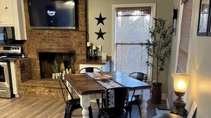 Una sala de estar con chimenea, una mesa de comedor y un televisor montado en la pared.