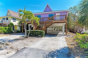 A two-story house with a wooden staircase leading to a covered patio area. - The Magic Dolphin B, great Holmes Beach location, steps to gulf beaches (Holmes Beach)
