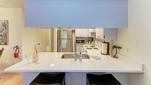 A modern kitchen with a central island, stainless steel appliances, and a minimalist design. - The Magic Dolphin B, great Holmes Beach location, steps to gulf beaches (Holmes Beach)