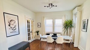 A dining area with a white table, chairs, and a bench. There are potted plants and framed pictures on the walls. - 🌇DoWnToWn HoUsE🏡 / 3min WALK to TrainSTATION & facilities / Clean-Spacious-Quiet (Harrison)