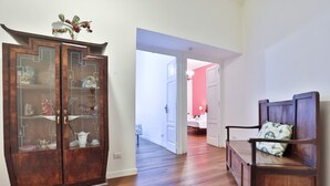 Um armário de madeira com portas de vidro, um banco com almofada e uma porta que dá para outro cômodo.
