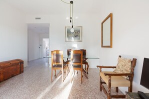 A room with a dining table, chairs, a wooden bench, a mirror, and a painting on the wall.