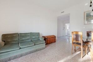A living room with a green sofa, a wooden chest, and a wooden chair.